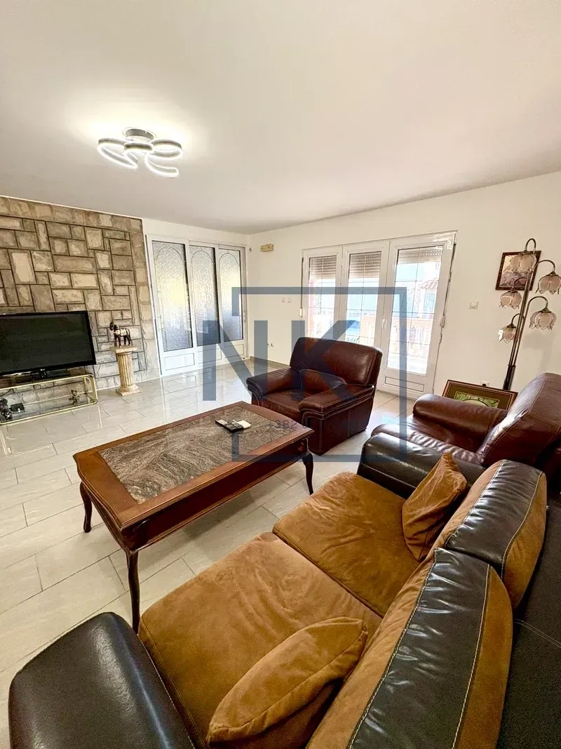 Living room with a sofa set, coffee table, and television on a stone wall.
