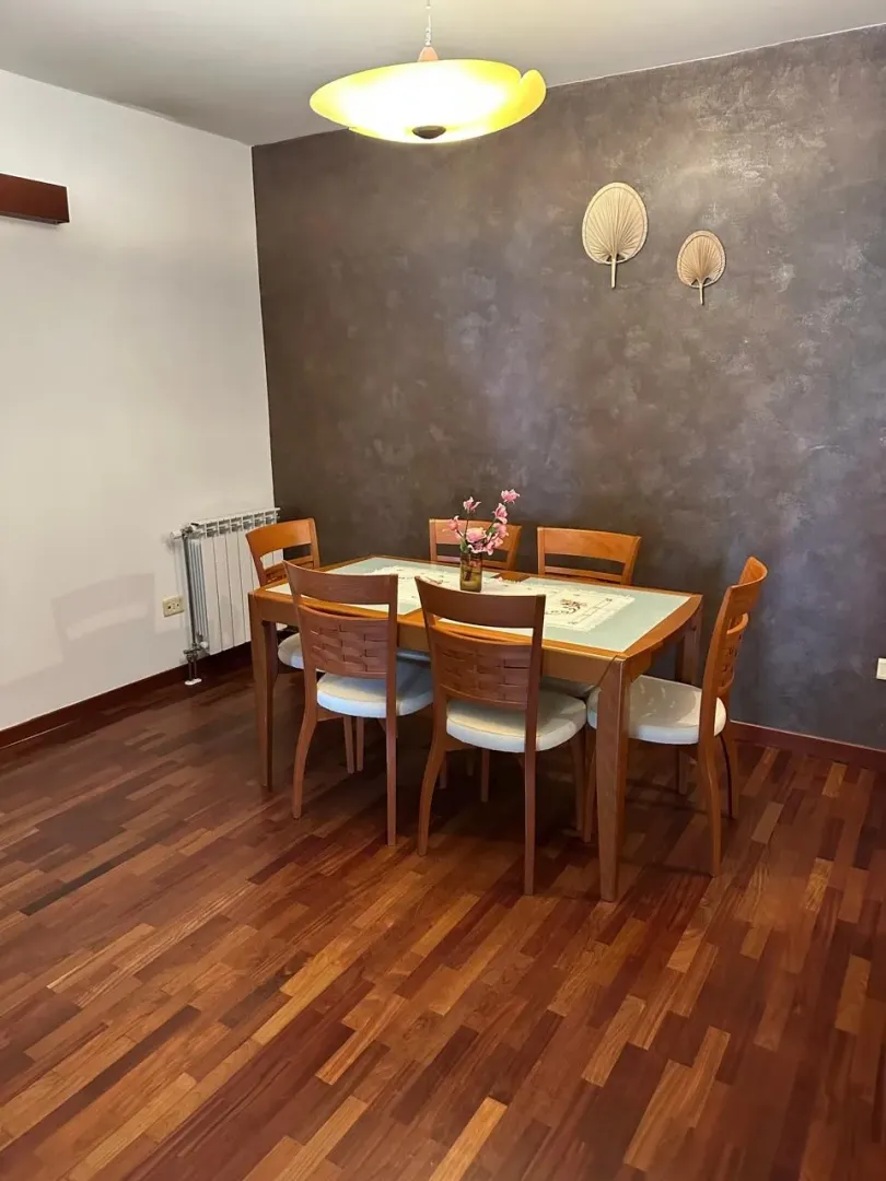 Dining area with a wooden table and chairs, hardwood flooring, and a decorative accent wall.