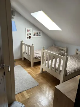 Potkrovna spavaća soba sa dva drvena kreveta i krovnim prozorom. - image 12