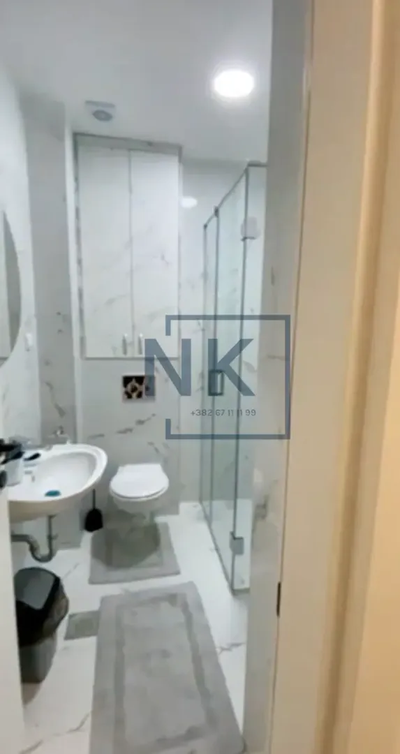 Modern bathroom with a walk-in shower, washbasin, and toilet.