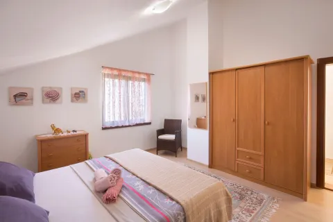 Spavaća soba sa bračnim krevetom, drvenim ormarom i komodom. - image 3