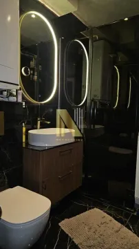Moderno kupatilo sa tamnim pločicama, umivaonikom i osvetljenim ogledalom. - image 11