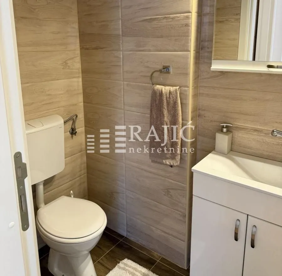 Small bathroom with a toilet, washbasin, and wood-effect tiles.