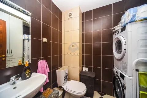 Kupatilo sa tamnim pločicama, umivaonikom, WC šoljom i mašinama za pranje i sušenje veša. - image 7