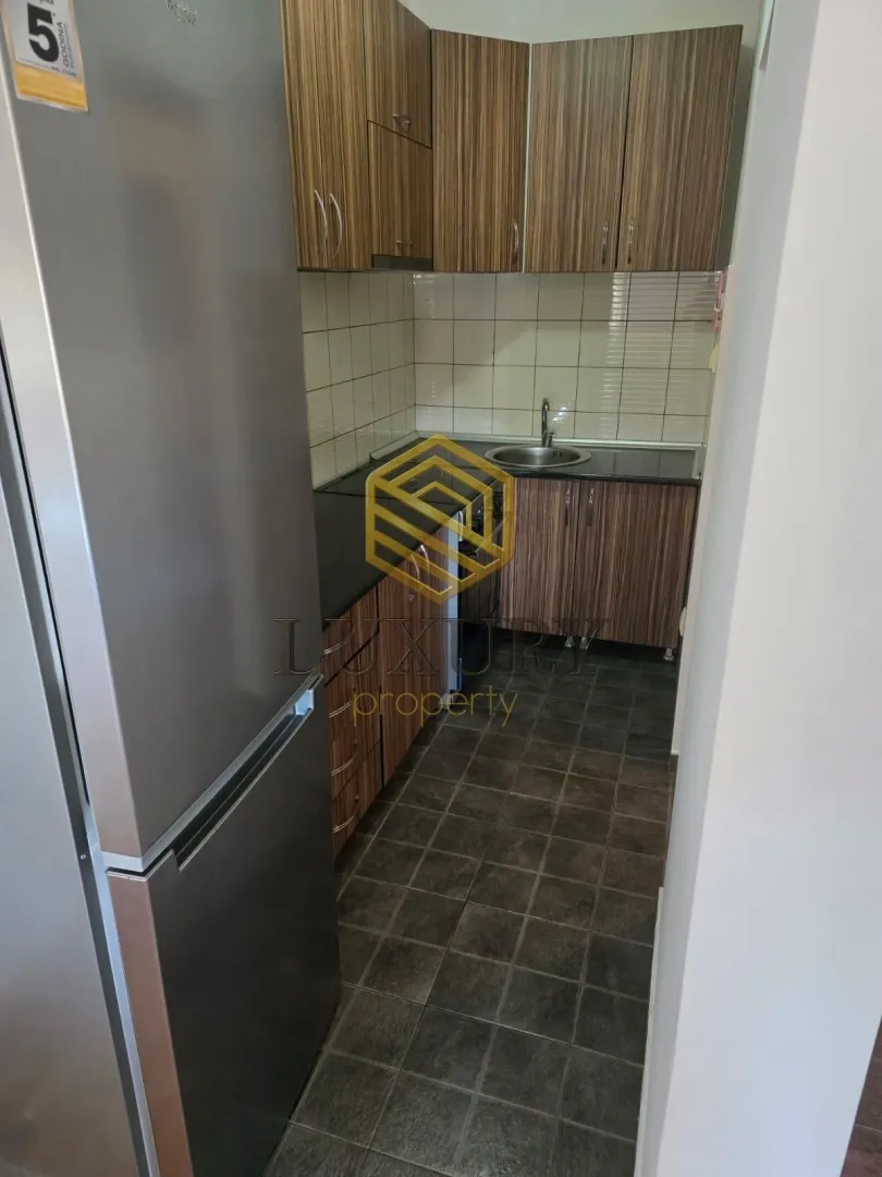 View of a smaller kitchen with wooden cabinets and a refrigerator.