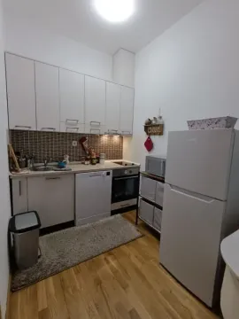Smaller equipped kitchen with white cabinets and a refrigerator. - image 4