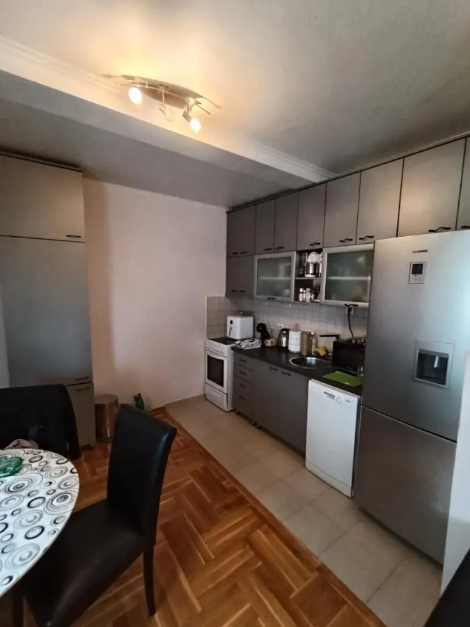 Kuhinja opremljena elementima i kućnim aparatima sa trpezarijskim stolom u prvom planu.