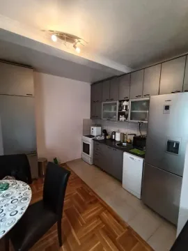 Kuhinja opremljena elementima i kućnim aparatima sa trpezarijskim stolom u prvom planu. - image 8