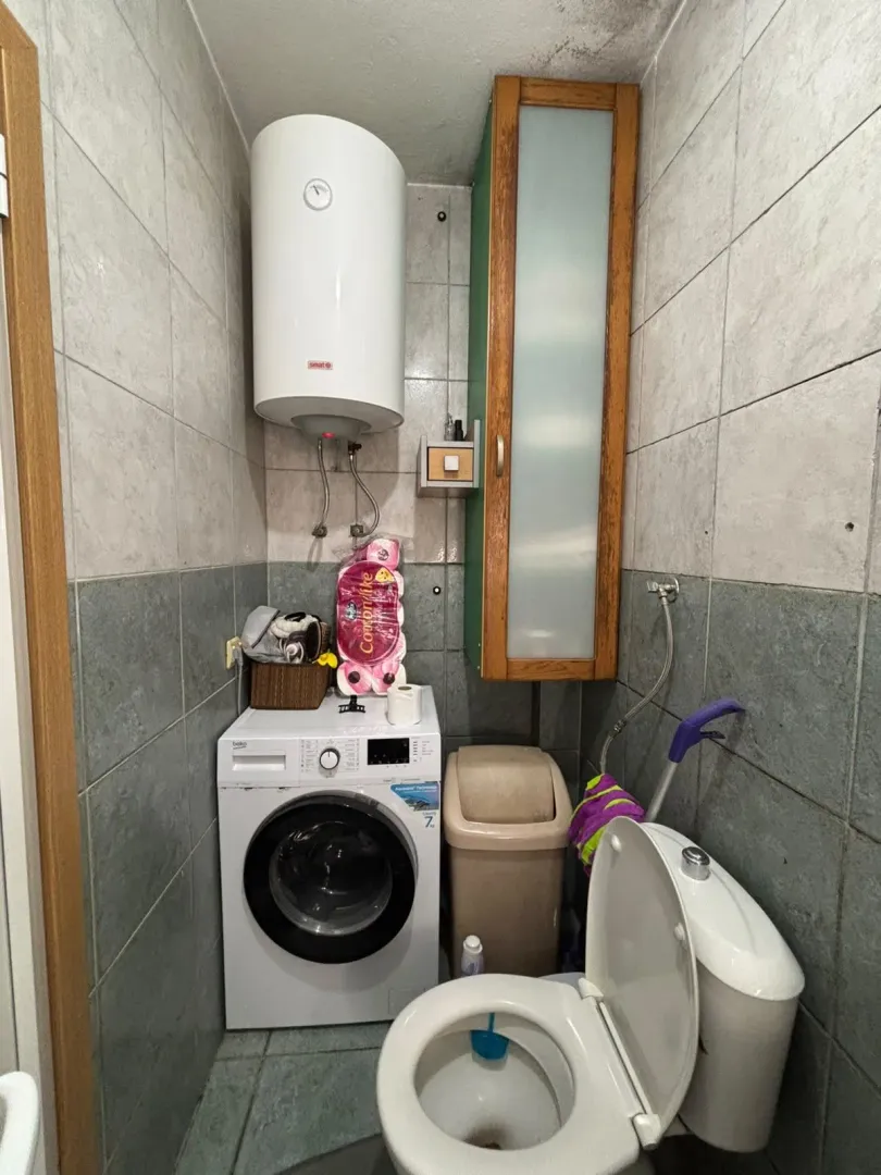 Bathroom with washing machine, water heater, and toilet.