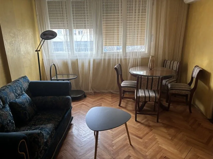 Dnevna soba sa garniturom, trpezarijskim stolom i parketom.