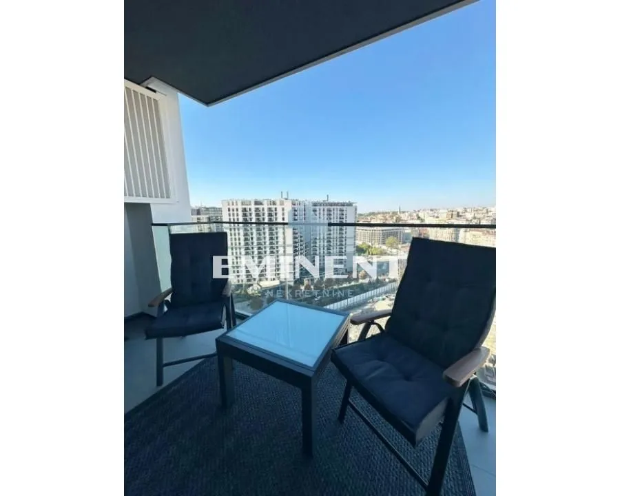 Small furnished balcony with seating set and city view.