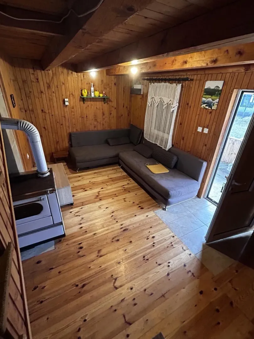 Dnevna soba u drvenom stilu sa ugaonim garniturama i peći na drva.