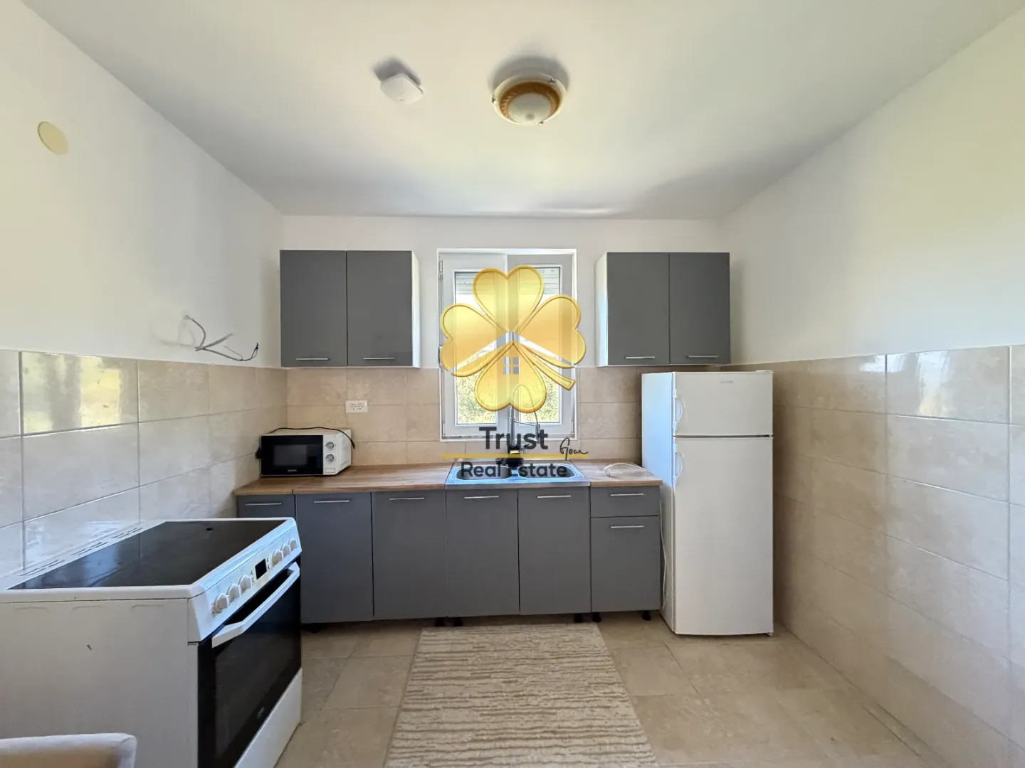 Smaller kitchen with grey cabinets and white appliances.