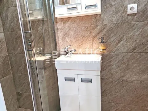 Small bathroom with a sink, shower cabin, and ceramic tiles. - image 10