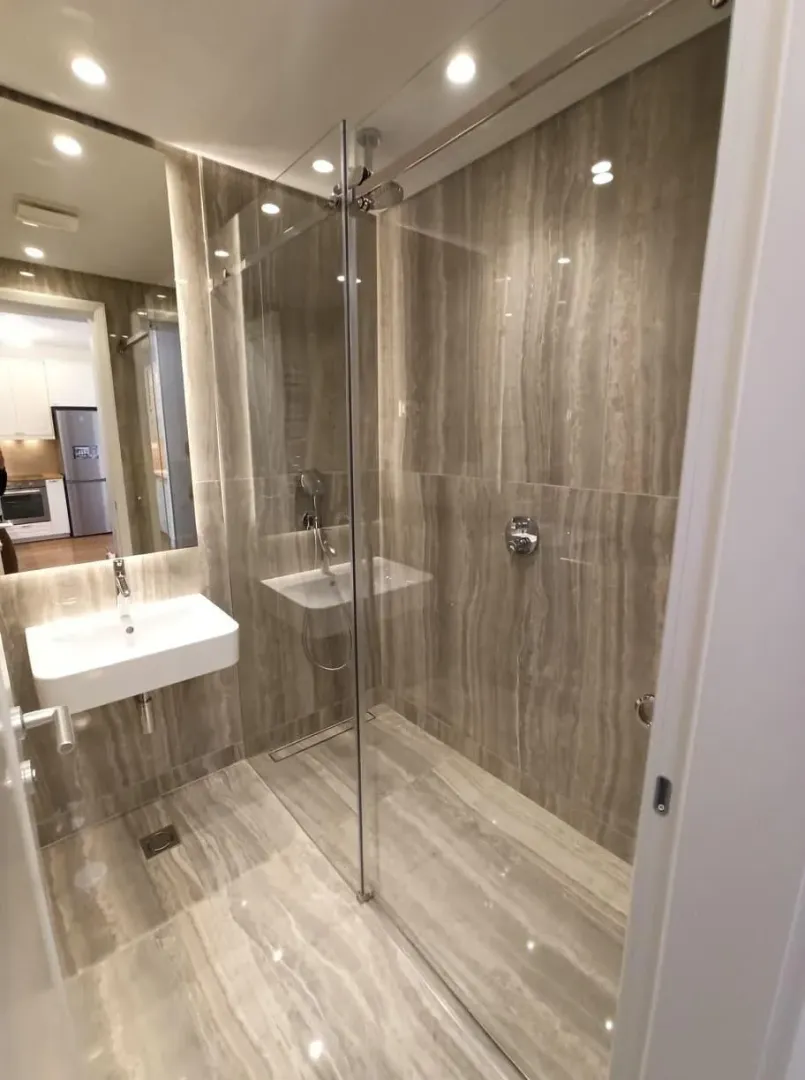 Modern bathroom with a glass-enclosed walk-in shower and a washbasin.