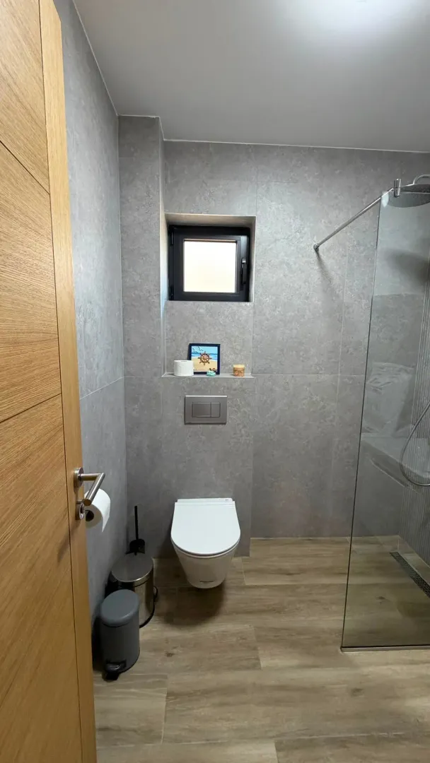 Modern bathroom equipped with a walk-in shower and grey tiles.