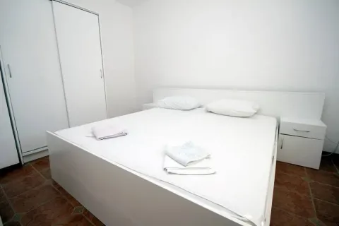 Svijetla spavaća soba sa velikim bračnim krevetom i bijelim ormarom. - image 9