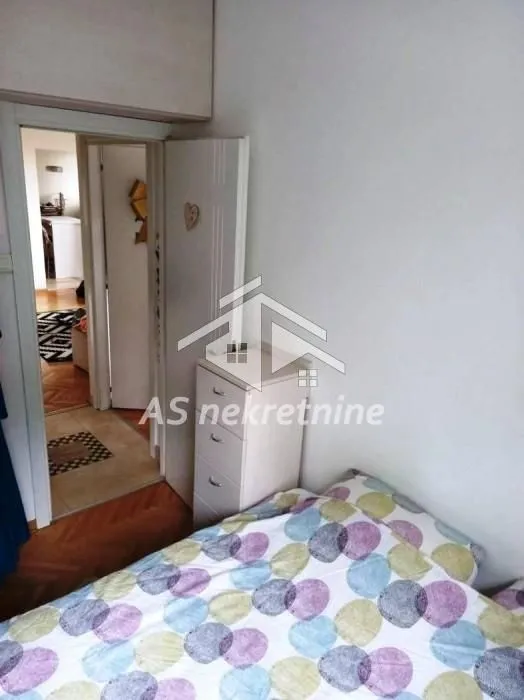 A view of the bed in the bedroom with a door leading to the hallway.