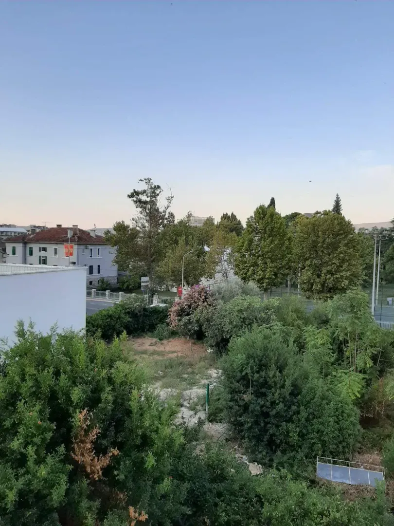Pogled iz nekretnine na zelene površine i okolne zgrade.