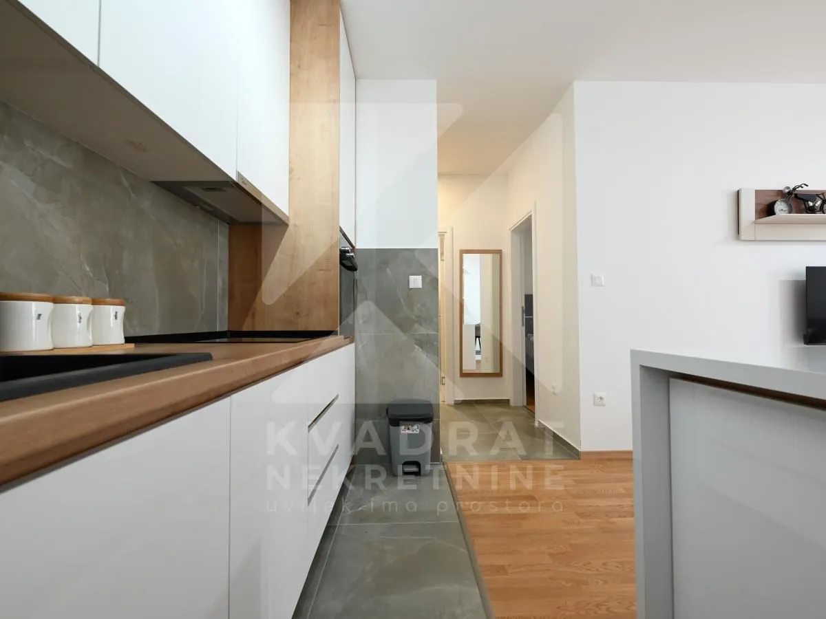 Modern kitchen with white units and wooden details.