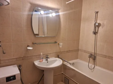 Bathroom equipped with a sink, bathtub, mirror, and tiles. - image 8