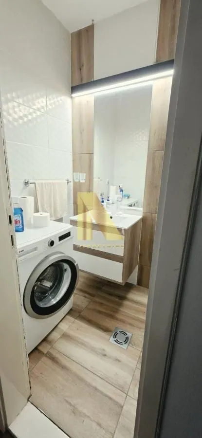Moderno kupatilo sa umivaonikom, ogledalom i veš mašinom.