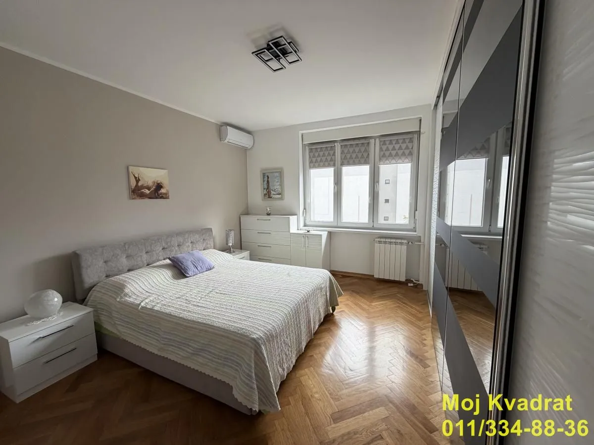 Furnished bedroom with a double bed, wardrobe, and hardwood flooring.