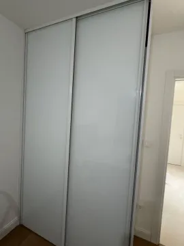 Built-in wardrobe with white glass sliding doors in a room. - image 10