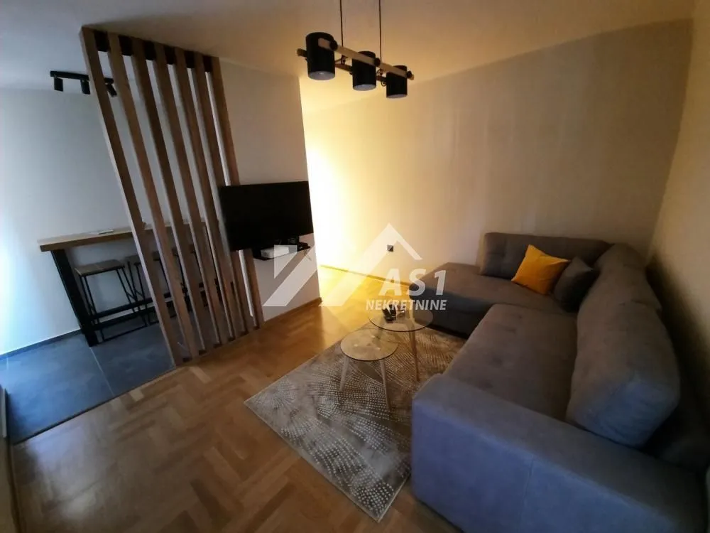Living room with a sectional sofa, coffee table, and a wooden partition toward the dining area.