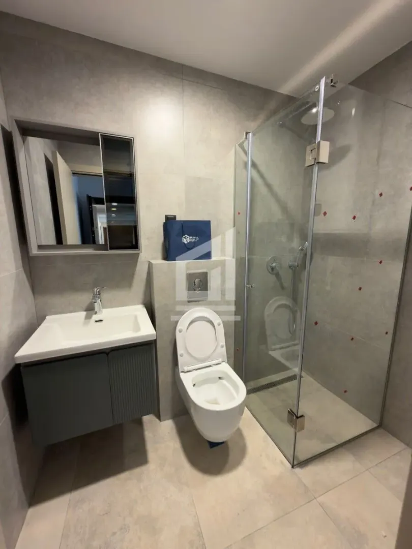 Moderno opremljeno kupatilo sa tuš kabinom, umivaonikom i WC šoljom.