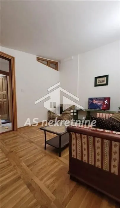Dnevna soba sa garniturom, stočićem i televizorom.