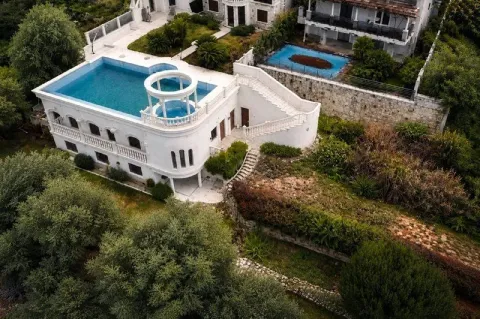 Aerial view of a white house with a rooftop pool and a garden surrounded by greenery. - image 3
