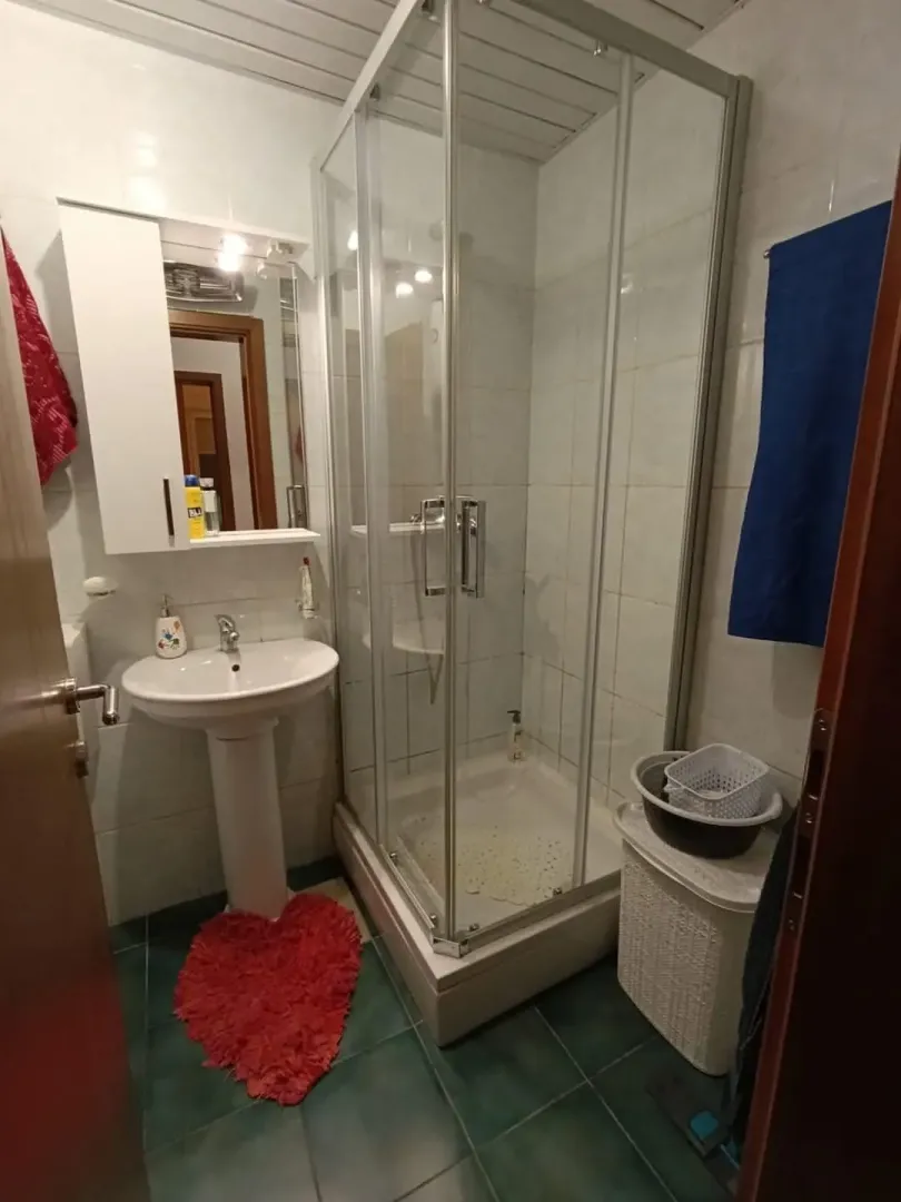 Malo kupatilo sa staklenom tuš kabinom i lavaboom.