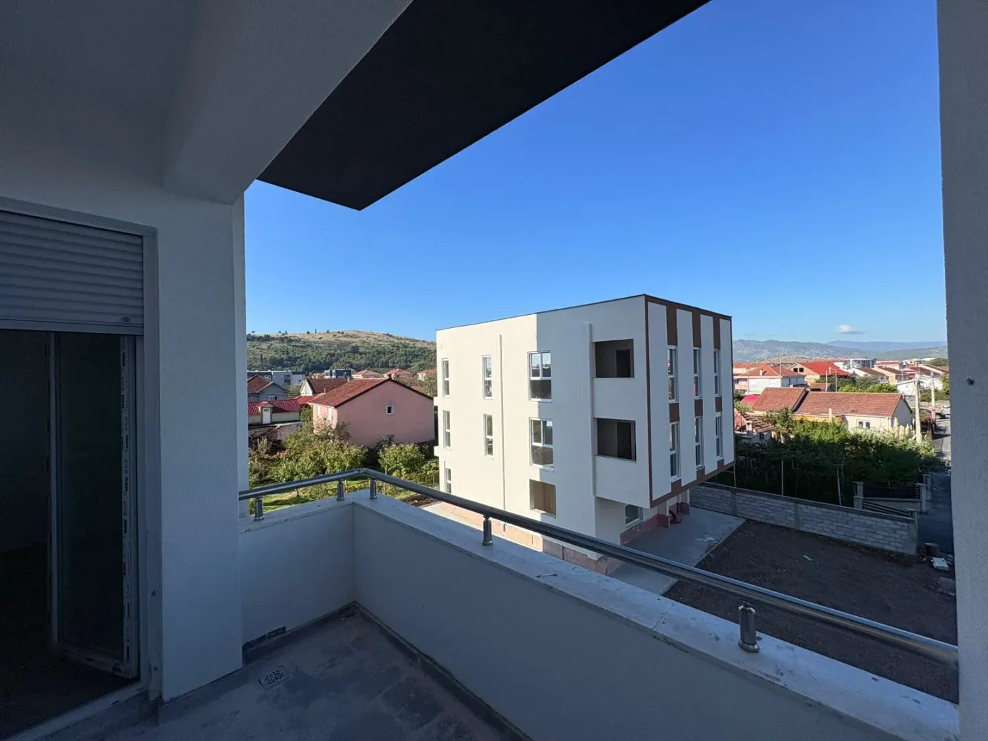 Pogled sa terase na okolne zgrade i pejzaž.