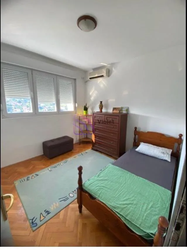 Spavaća soba sa jednim krevetom, komodom i prozorom.