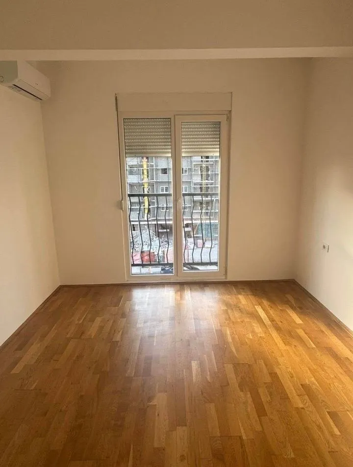 Empty room with parquet flooring and balcony doors.
