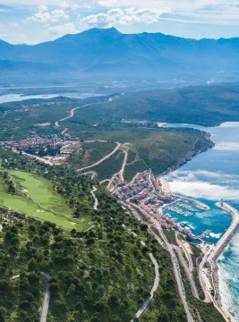 Pogled iz vazduha na obalu, naselje i marinu sa planinskim pejzažem u pozadini. - image 6