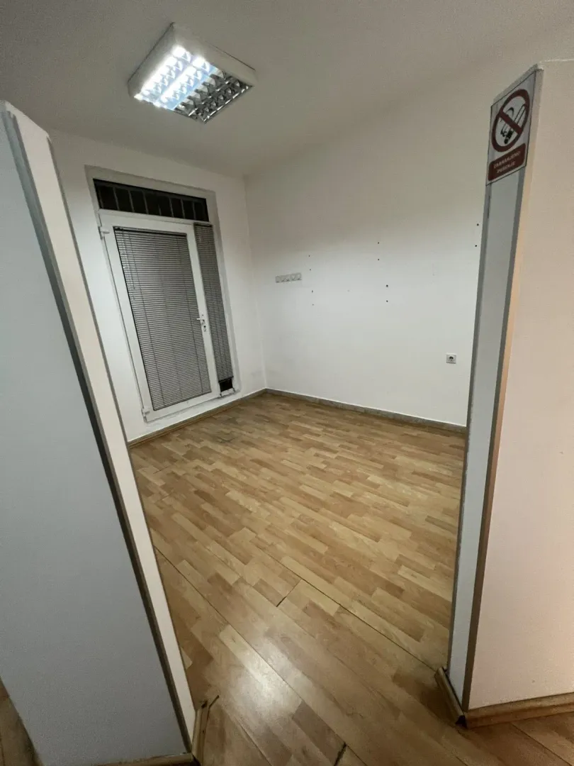 An empty room with laminate flooring, white walls, and a glass balcony door.