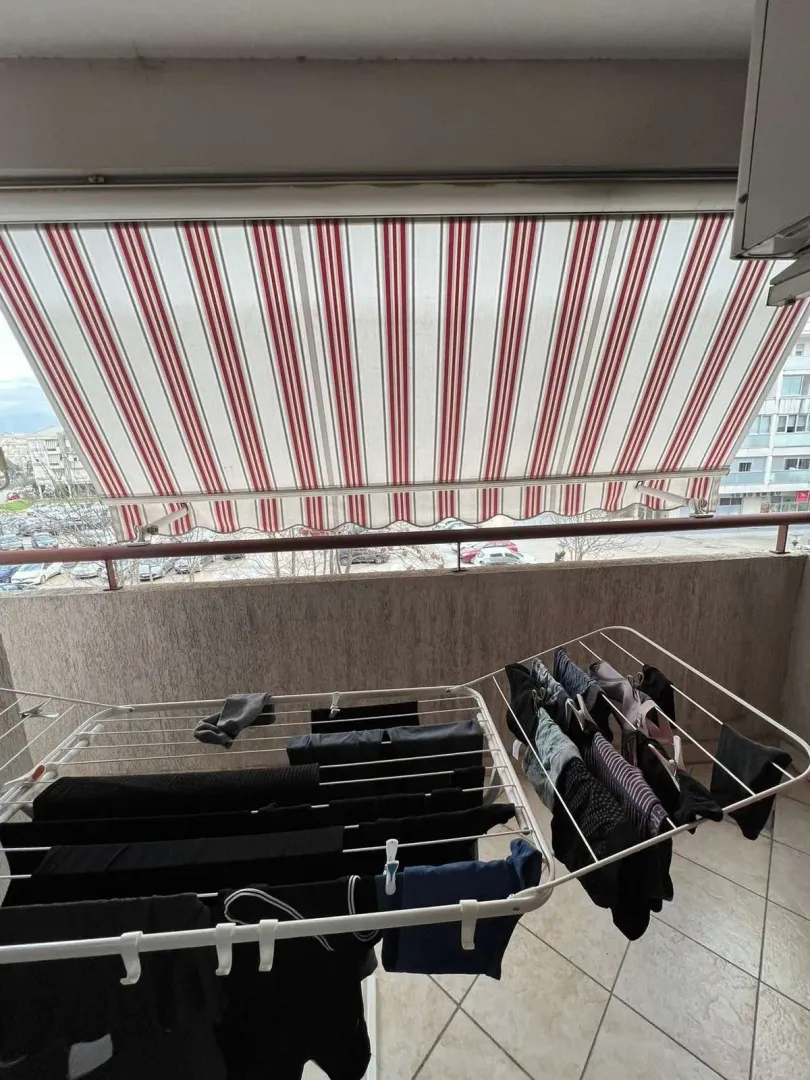Balkon sa prugastom tendom i sušilicom za veš.