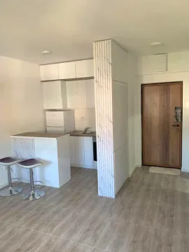 Small white kitchen with a breakfast bar and bar stools inside the apartment. - image 2
