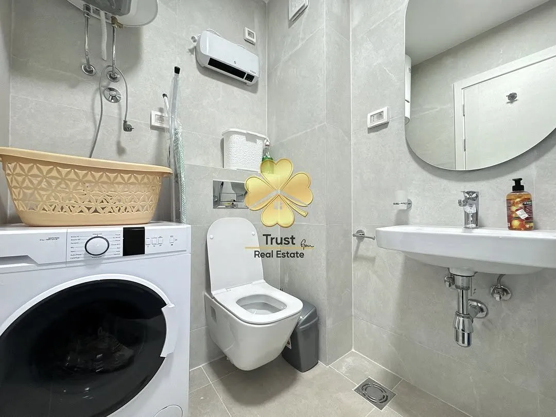Moderno opremljeno kupatilo sa veš mašinom, umivaonikom i WC šoljom.