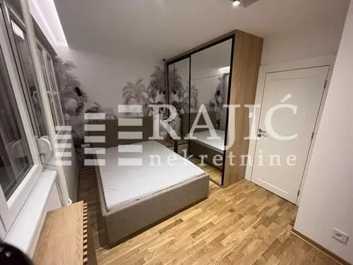 Modern bedroom with a double bed, large mirrored wardrobe, and wooden flooring.