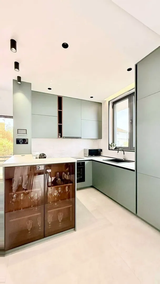 Modern kitchen with green cabinetry and built-in appliances.