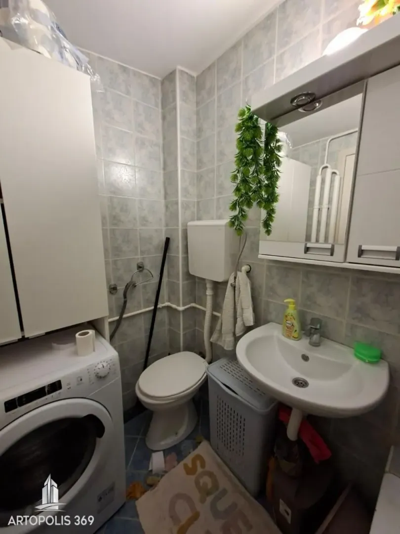 Manje kupatilo sa umivaonikom, WC šoljom, ormarićem i mašinom za veš.
