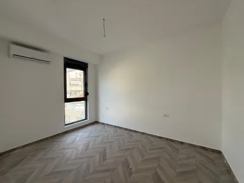 Prazna soba sa bijelim zidovima, drvenim podom i klima uređajem. - image 4
