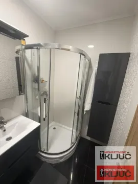 Kupatilo sa tuš kabinom, umivaonikom i crnim ormarićem. - image 6