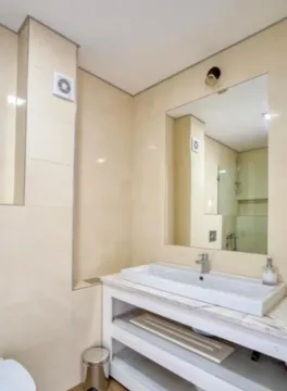 Bathroom with a washbasin, large mirror, and light-toned tiles. - image 4