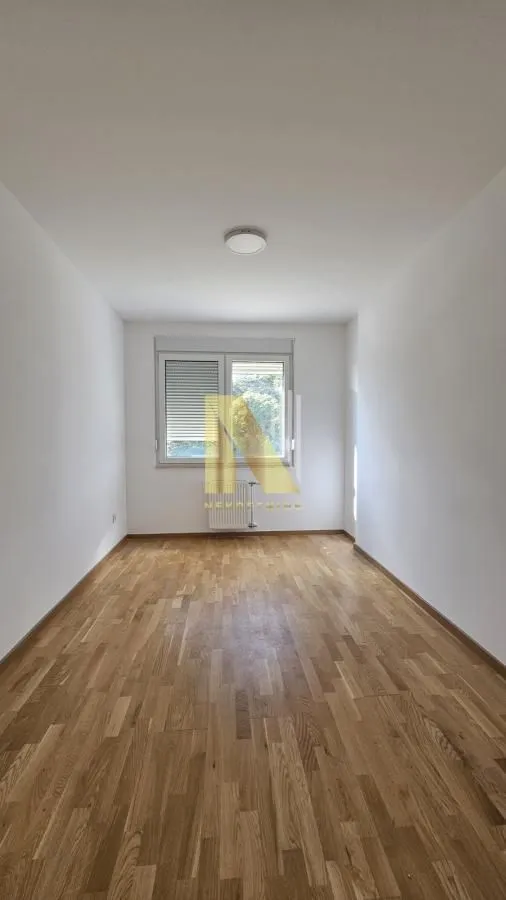 Prazna soba sa parketom na podu i prozorom.