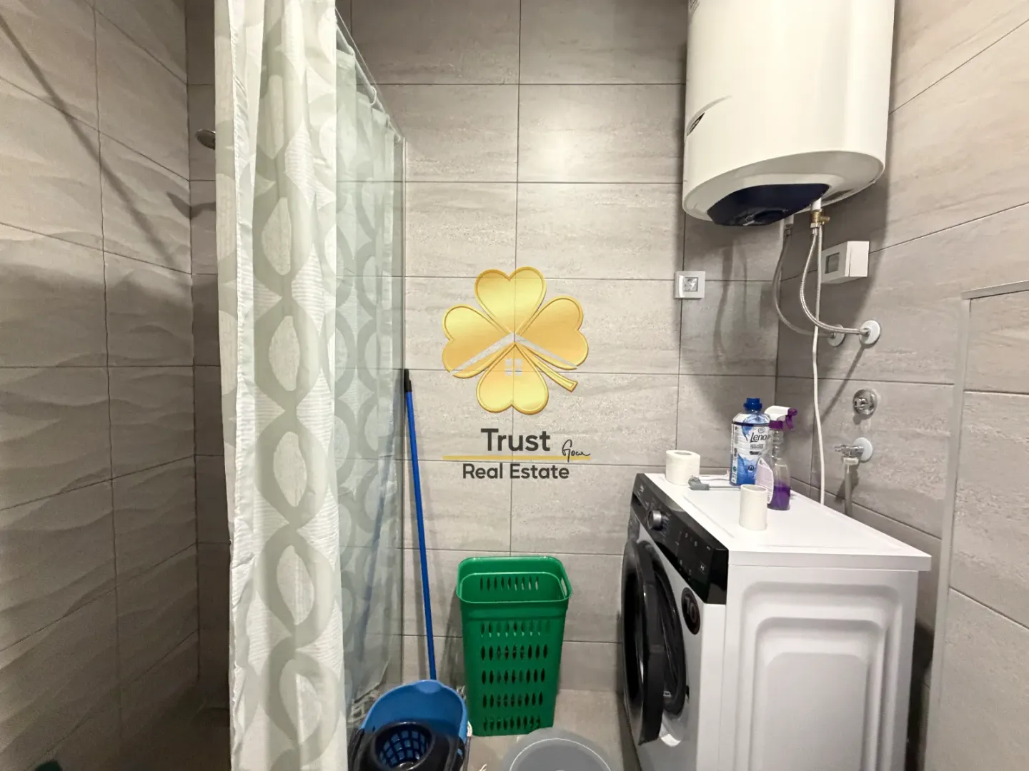 Smaller bathroom with a shower cabin, washing machine, and water heater.