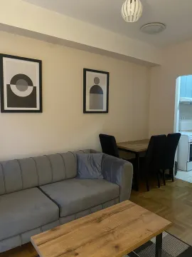 Living room with a grey sofa, wooden table, and a dining area in the background. - image 5